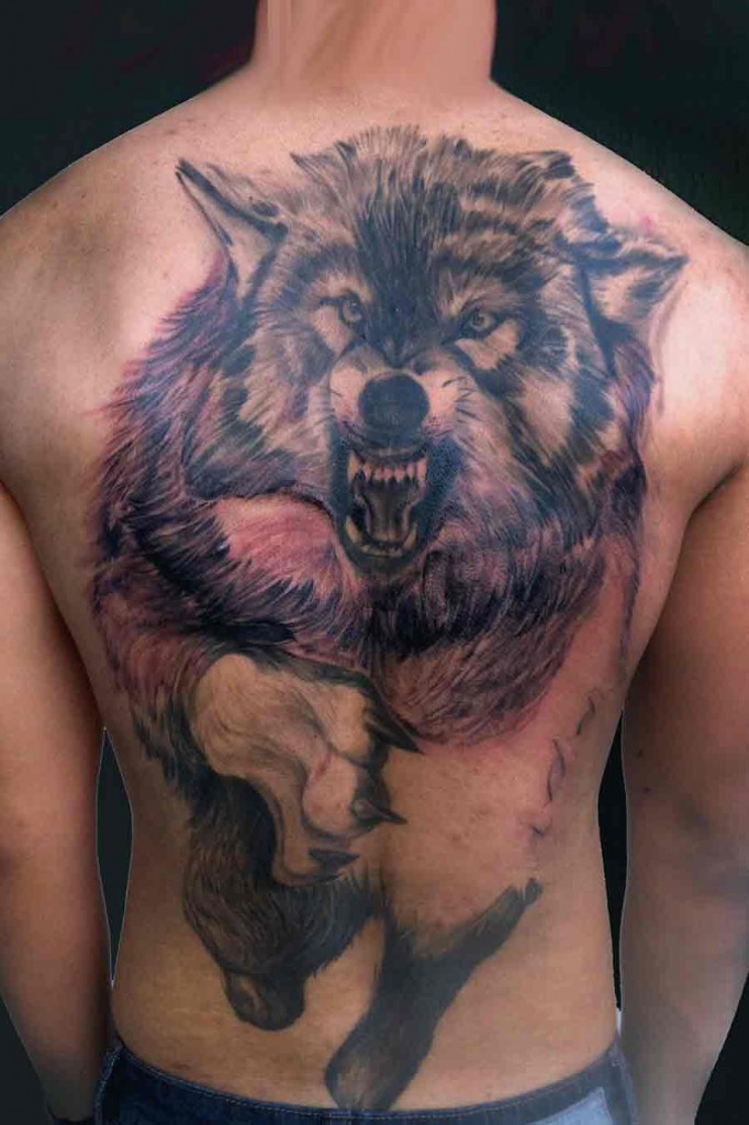 Angry wolf tattoo on back representing strength & power