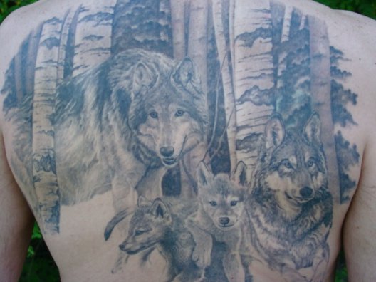 Calm faced Wolf's family in forest tattoo on back representing love with family and nature