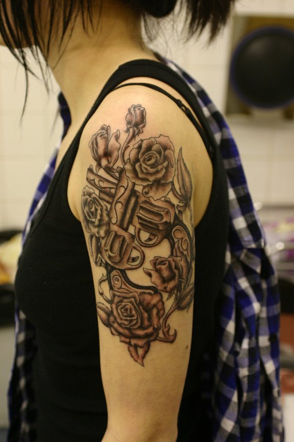 Fantastic Crossed Guns and Roses Tattoo On Girl's Shoulder
