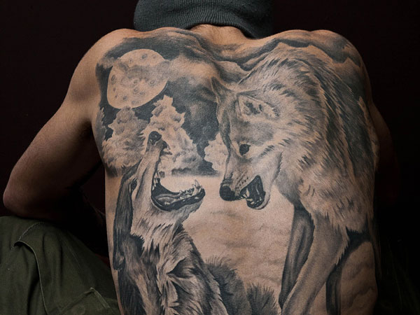 Fighting Wolves and moon portrait tattoo on back