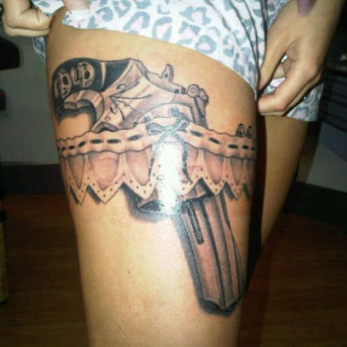 Grey Ink Pistol in Garter Tattoo On Girl Right Thigh