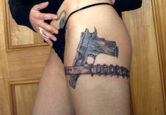 Hand Pistol in bullet holder garter strap tattoo on girl's left thigh