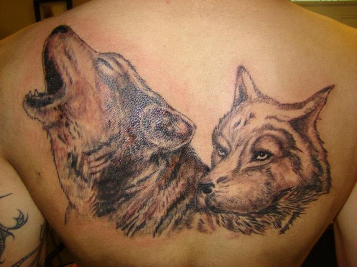 Howling wolf with a calm wolf tattoo on upper back