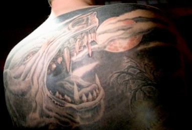 Wild wolf howling at moon tattoo on back
