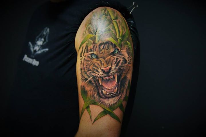 Realistic roaring tiger in grass tattoo on half sleeve
