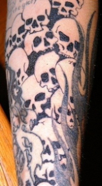 Pile of skulls tattoo on forearm