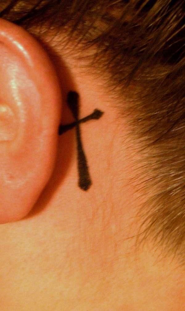 Black Cross Tattoo On Behind The Ear By Janis