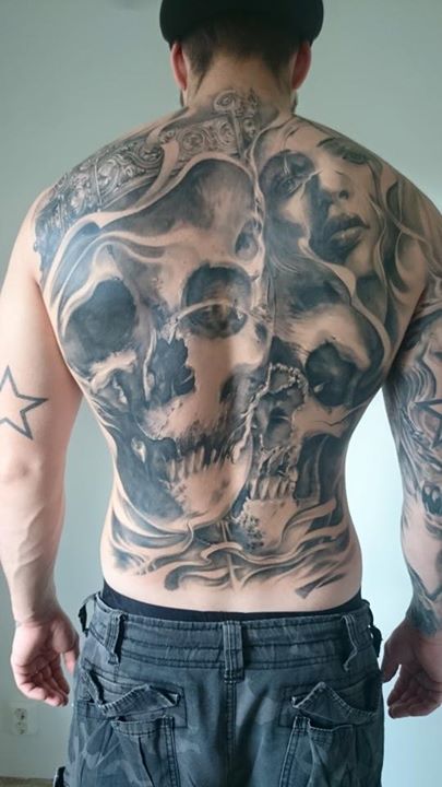 Black and grey skulls and face tattoo on back