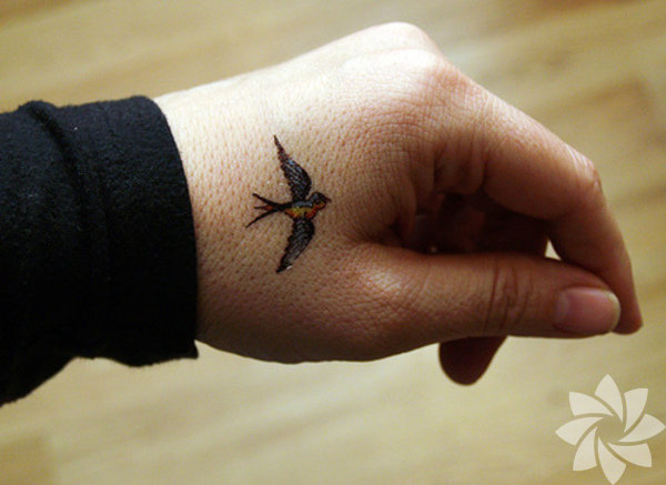 Colorful Little Flying Swallow Tattoo On Hand