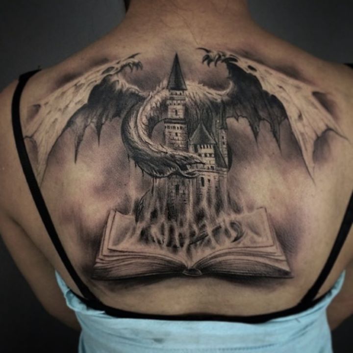 Flying dragon with buildings and burning book tattoo on back