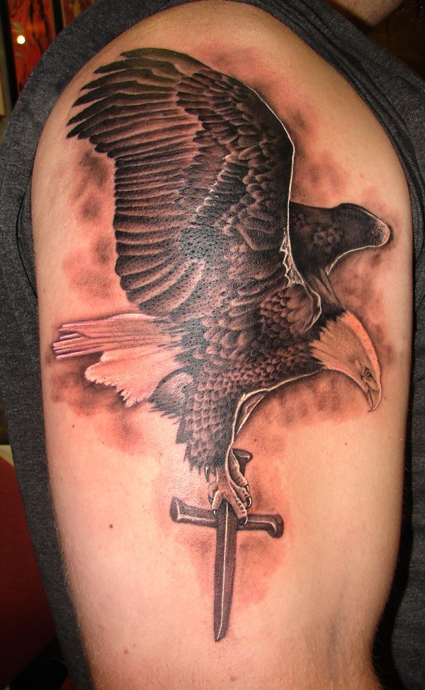 Black And Grey Flying Eagle With cross Tattoo On Shoulder