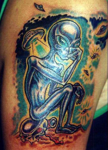 Sad Alien Sitting On Skull Tattoo On Arm