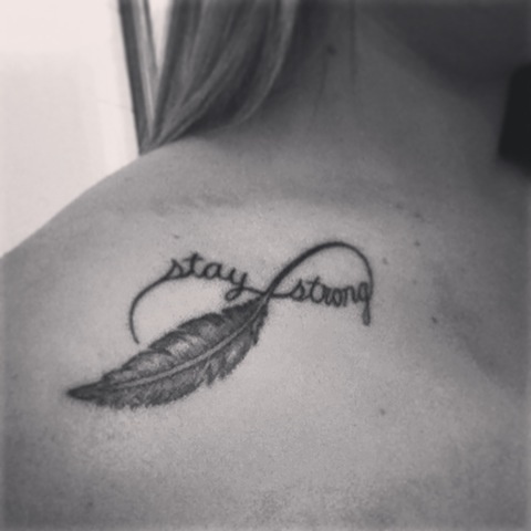 Stay Strong in infinity symbol and feather tattoo on girl’s shoulder