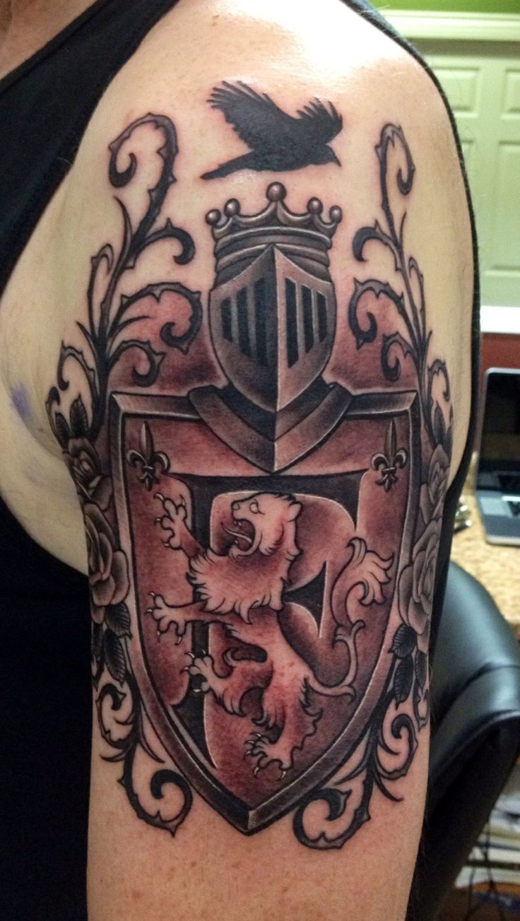 Black And Grey Roaring Lion In Family Crest Tattoo On Man Left Half Sleeve