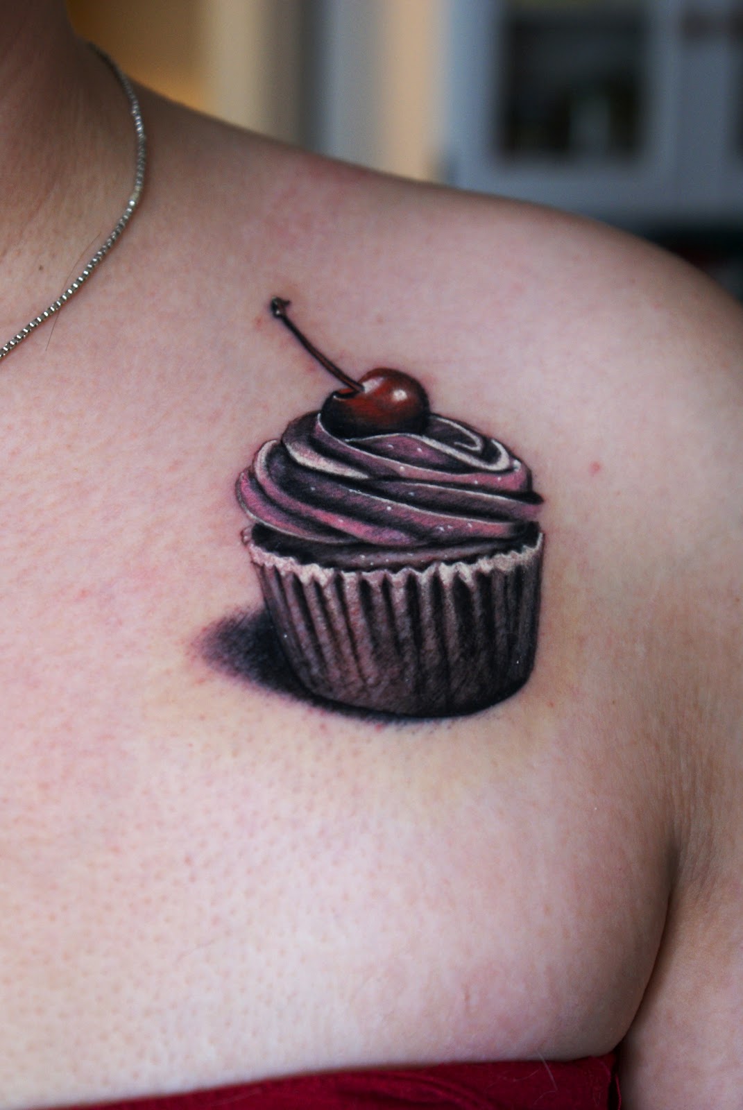 Black Cupcake Tattoo On Girl Front Shoulder