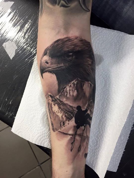 Black and grey eagle with climbing mountaineer tattoo on forearm