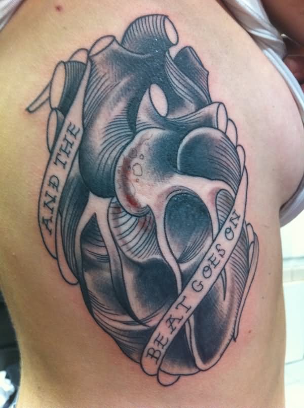 Black and grey human heart tattoo on girl’s siderib