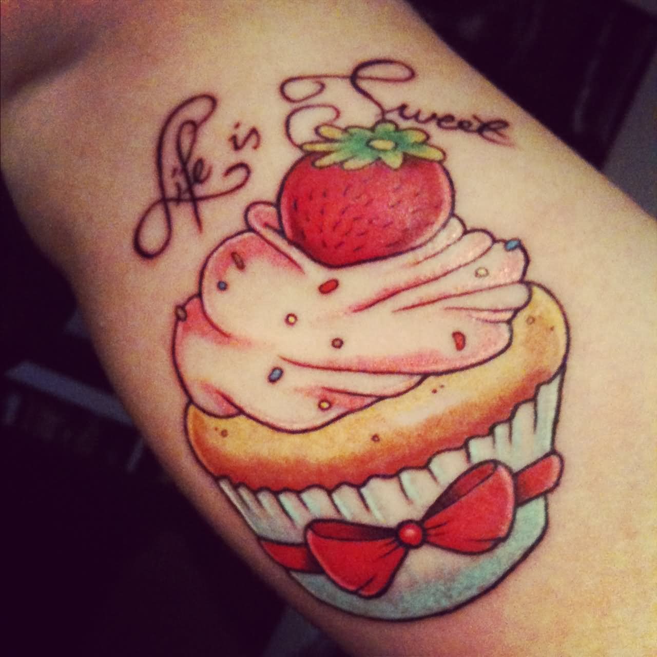 Colorful Strawberry On Cupcake With Ribbon Bow Tattoo Design