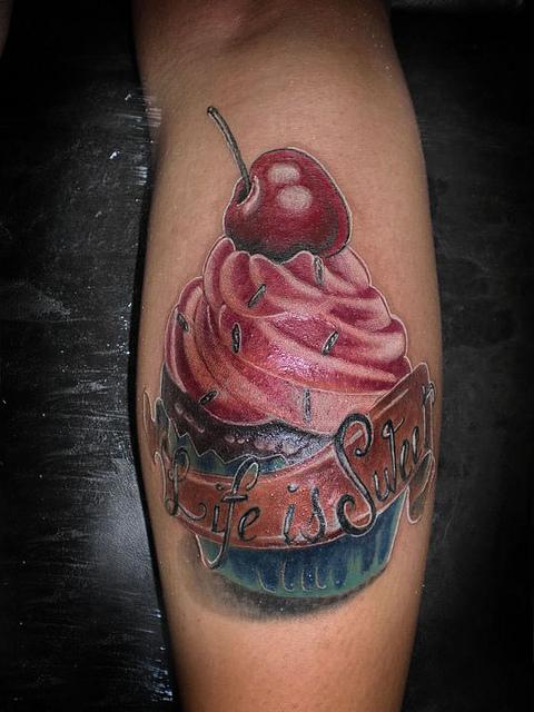 Red Cheery On Colorful Cupcake With Banner Tattoo On Leg Calf By Jean Rocha
