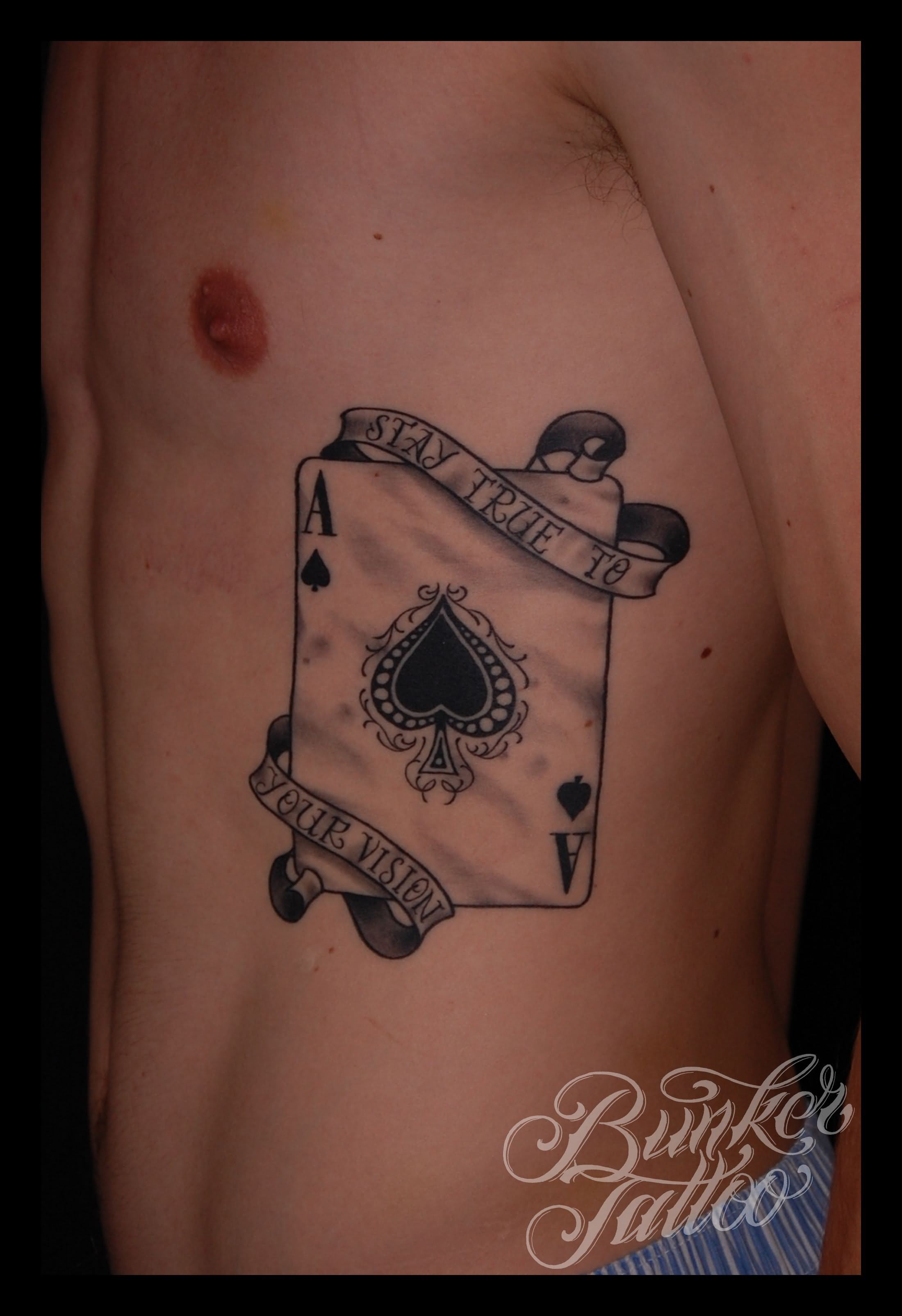 Black Ace Of Spade With Banner Tattoo On Man Side Rib