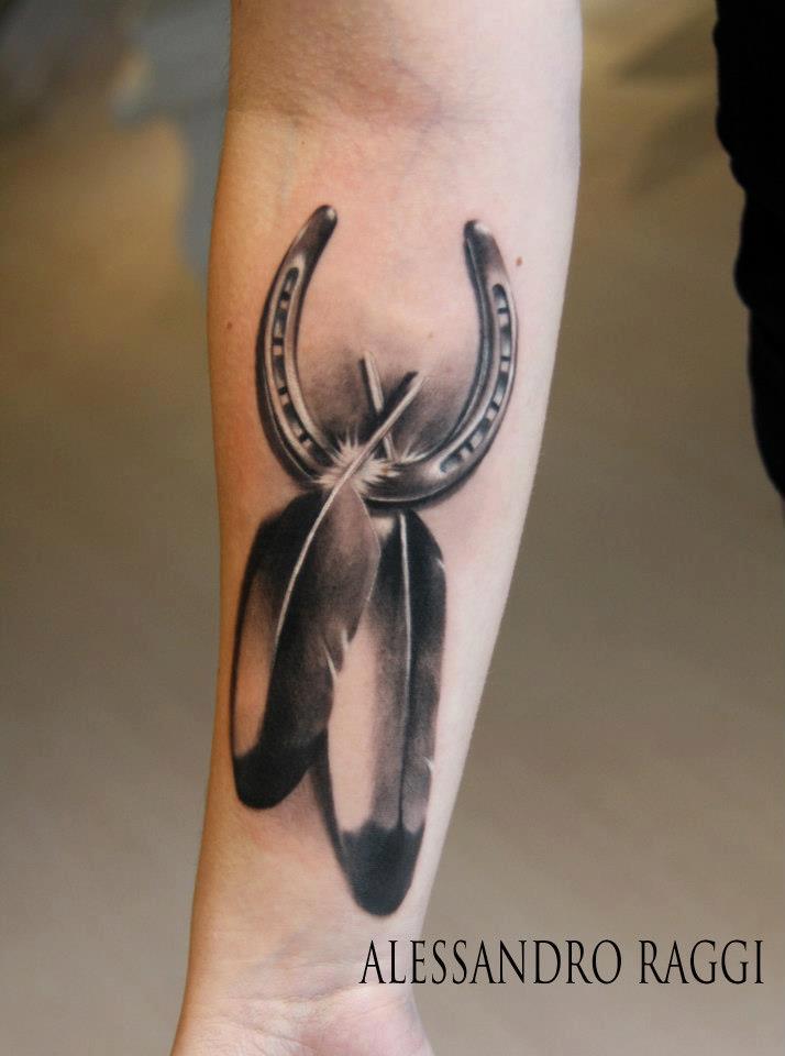 Black And Grey Horseshoe With Two Feather Tattoo On Forearm By Alessandro Raggi