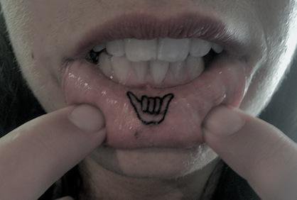 Black Hang Loose Hand Tattoo On Girl Inner Lip