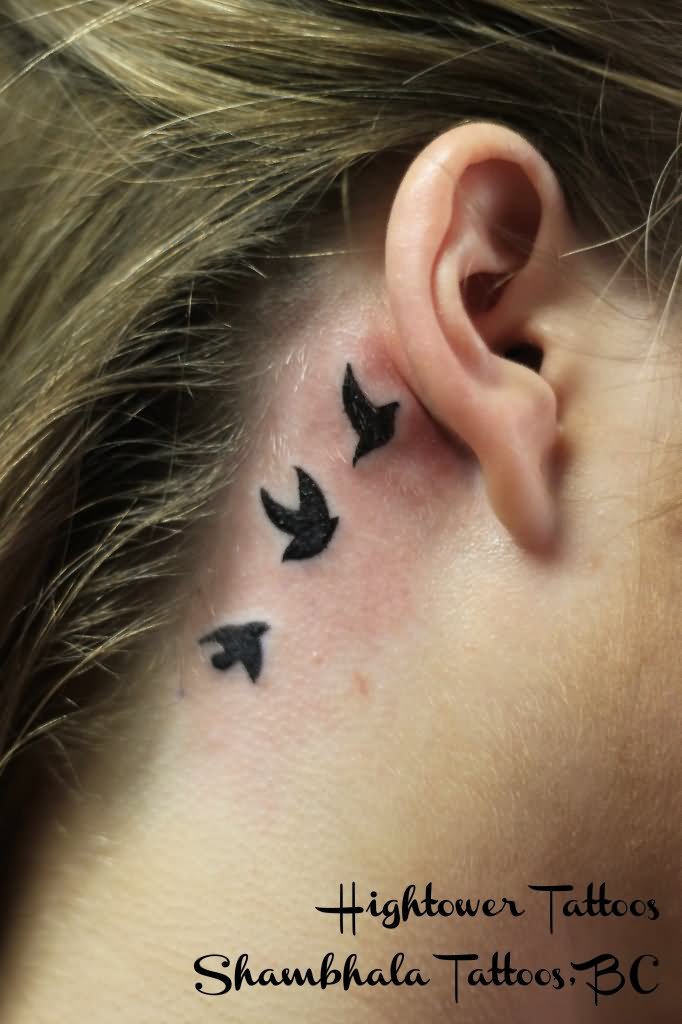 Black Tiny Three Flying Birds Tattoo On Girl Behind The Ear