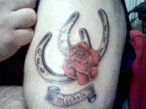 Grey Two Horseshoe With Red Rose And Banner Tattoo On Bicep