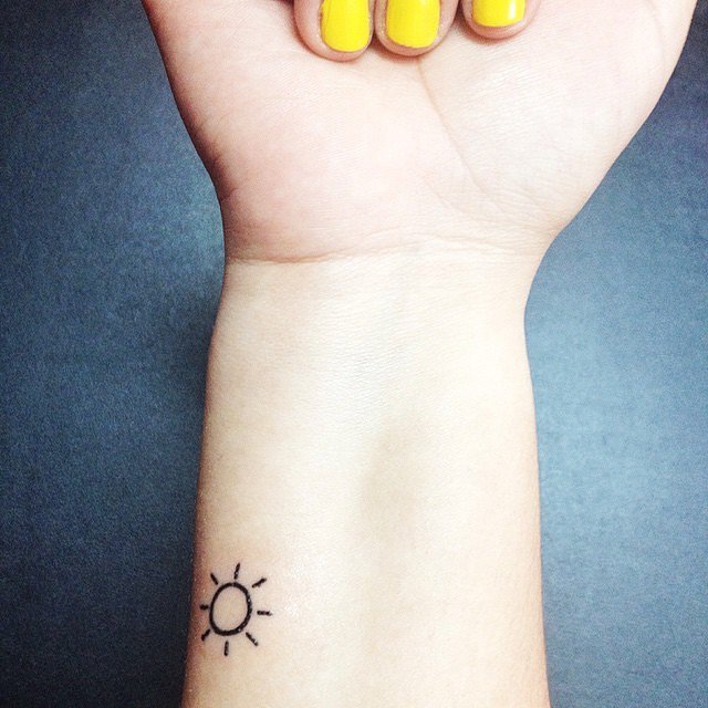 Black Tiny Sun Tattoo On Girl Wrist