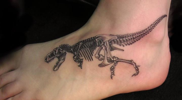 Black And Grey Dinosaur Skeleton Tattoo On Foot