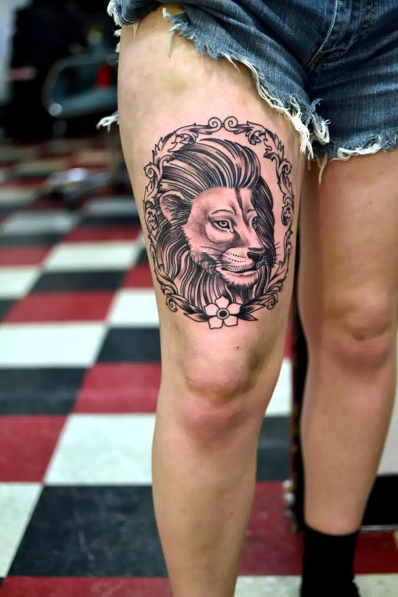 Black And Grey Lioness Head In Frame Tattoo On Girl Thigh