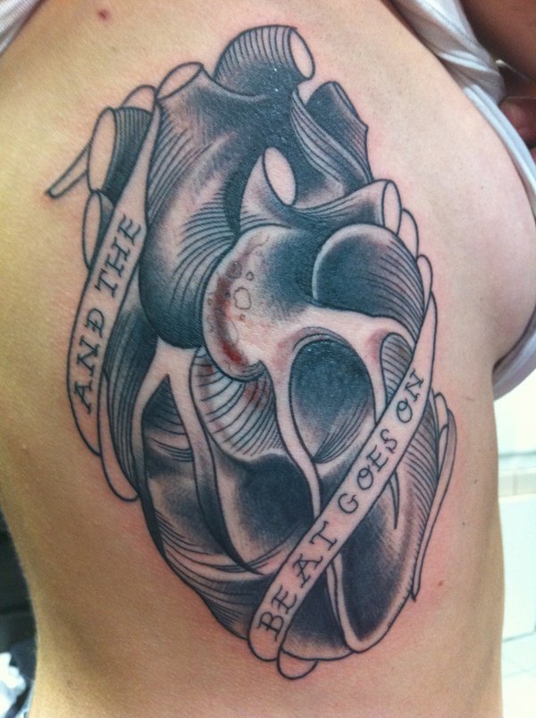 Black And Grey Real Heart With Banner Tattoo On Man Chest