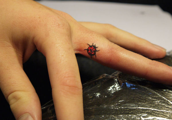 Black And Red Little Ladybird Tattoo On Finger