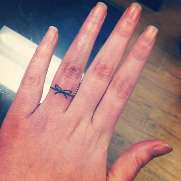 Black Thread Bow Ring Tattoo On Girl Finger
