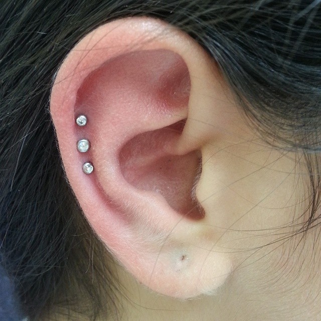 Triple Cartilage Piercing On Girl Right Ear With Diamond Studs