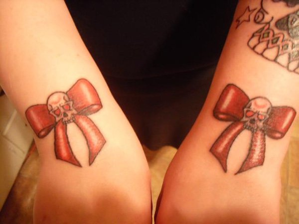 Two Skull On Red Bows Tattoo On Both Upper Wrist By Evadeone