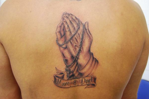 Amazing Rosary Cross In Praying Hand With Banner Tattoo On Upper Back