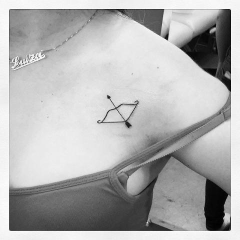 Black Bow And Arrow Tattoo On Girl Collarbone