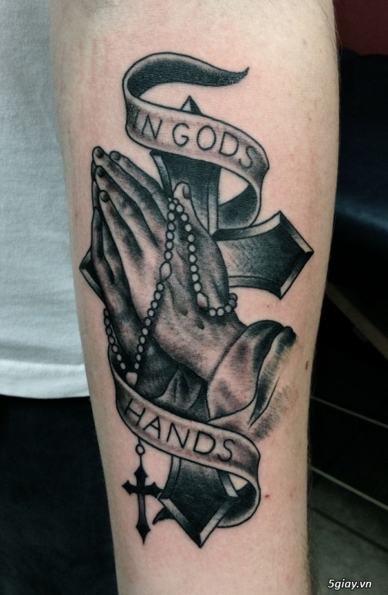 Black Ink Praying Hands With Cross And Banner Tattoo Design