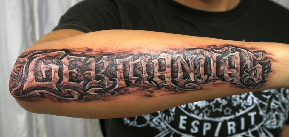 Black And Grey Germanitas Lettering Tattoo On Right Forearm