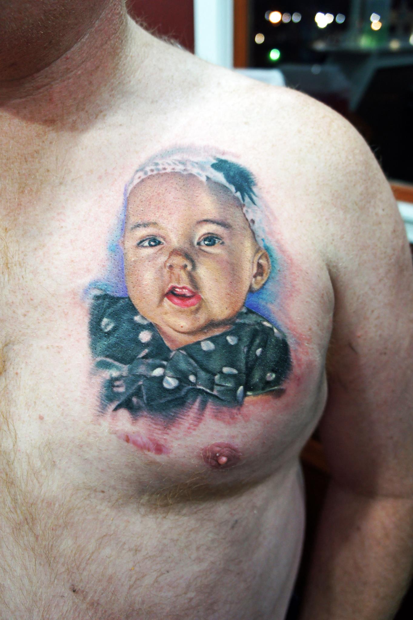 Colorful Baby Face Tattoo On Man Left Chest