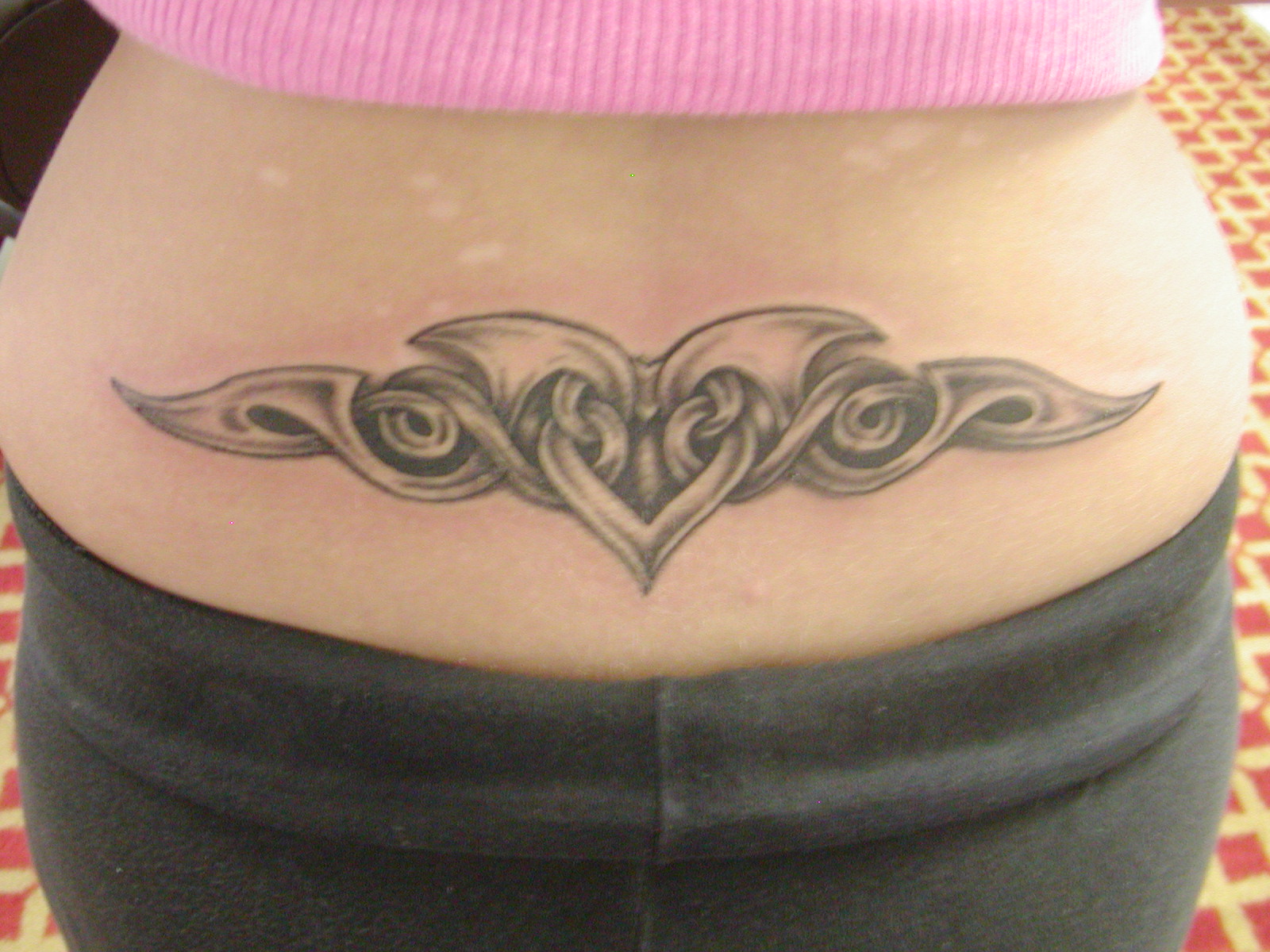 Grey Ink Celtic Heart With Swirl Tattoo On Girl Lower Back By Ruchi