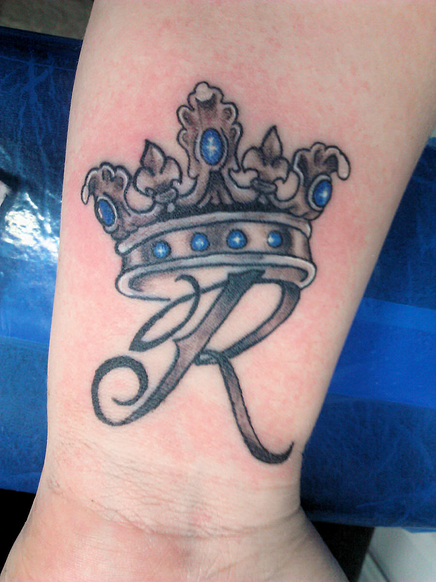 Grey Ink R With Crown Tattoo On Wrist