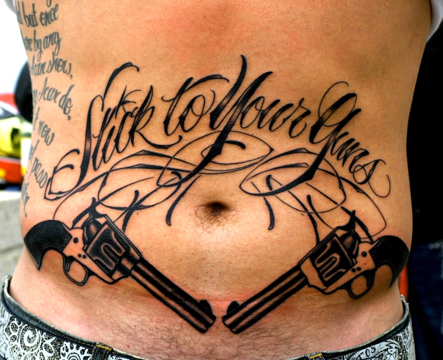 Stick To Your Guns Lettering With Two Guns Tattoo On Man Stomach