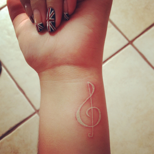 White Ink Violin Key Tattoo On Girl Left Wrist