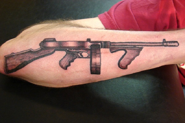 Black And Grey Tommy Gun Tattoo On Forearm