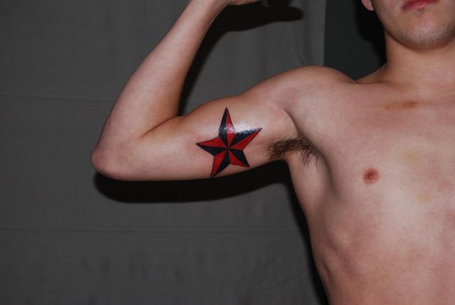 Black And Red Nautical Star Tattoo On Inner Bicep
