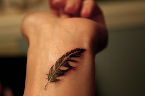 Black Ink Feather Tattoo On Wrist