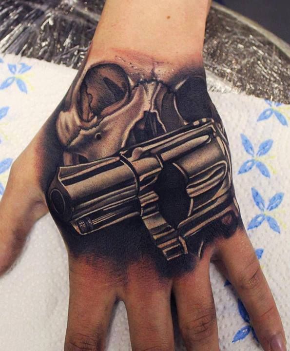 Black Ink Skull With Gun Tattoo On Hand