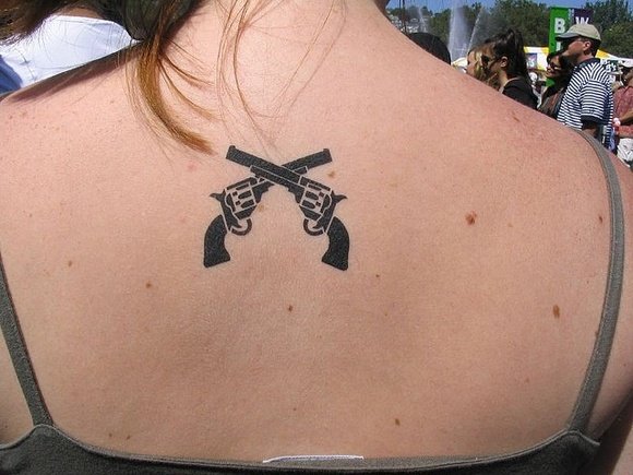 Black Two Crossing Gun Tattoo On Girl Upper Back